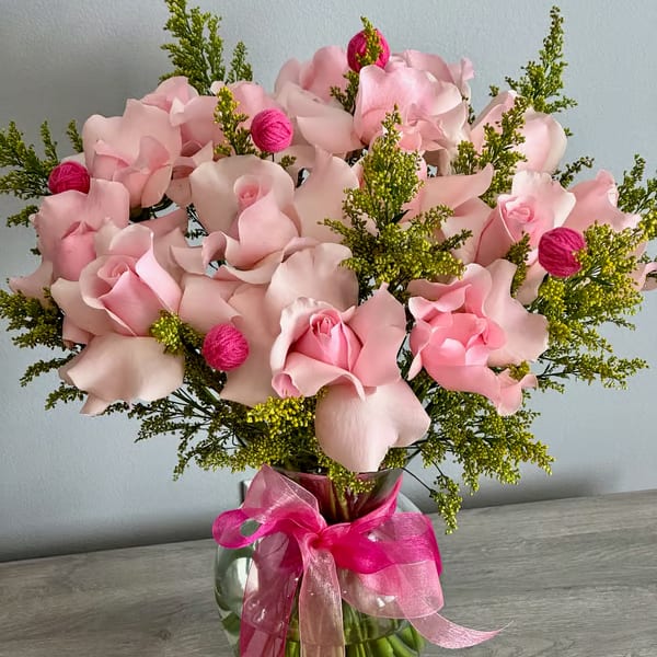 Pink rose bouquet in a glass vase with a bright ribbon