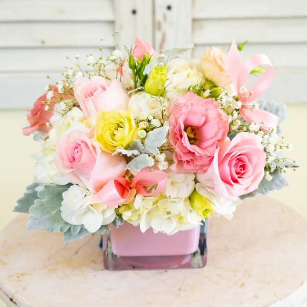 Pink and white bouquet in a square glass vase with ribbon accents