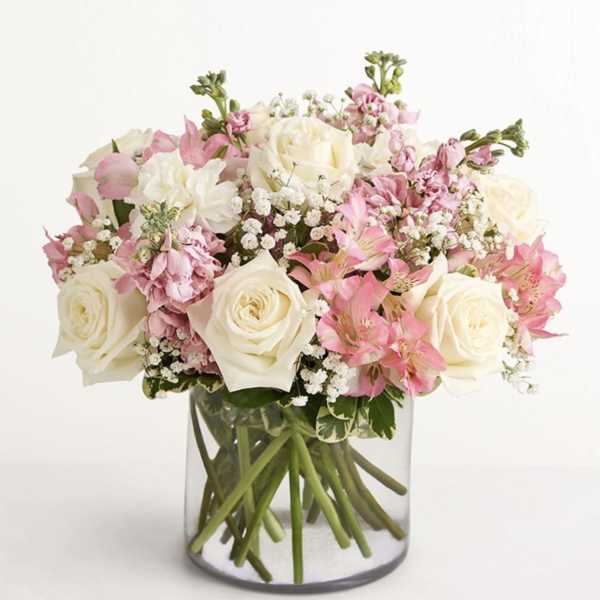 Pink and white roses arranged in a clear glass vase