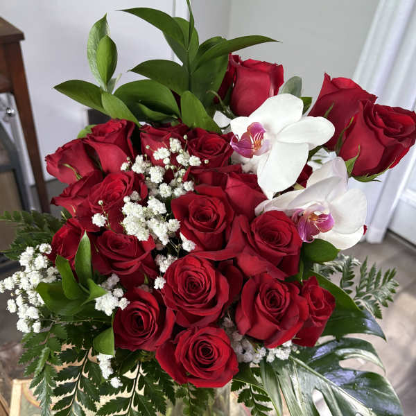 Bouquet of red roses with white orchids and baby's breath in a glass vase