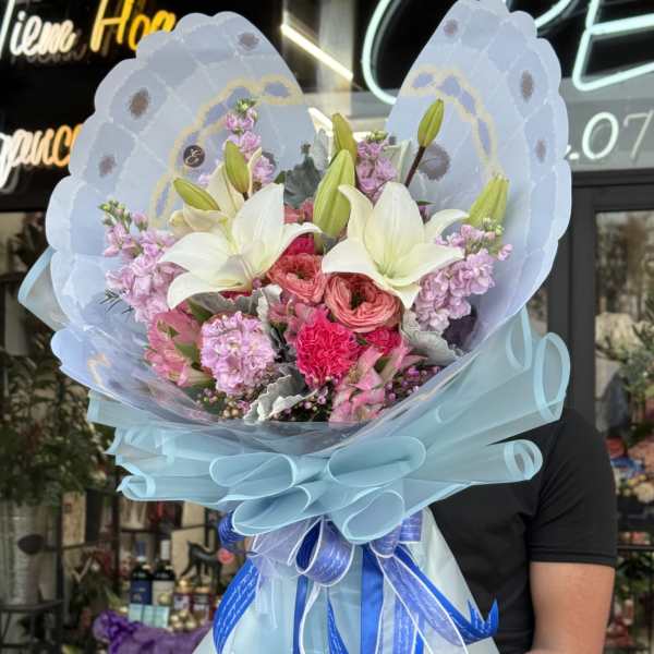 Bouquet of white lilies and pink flowers wrapped in blue paper