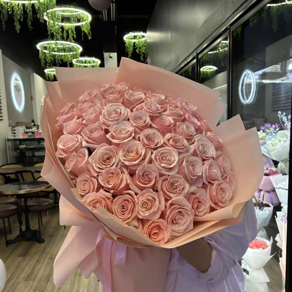 Large bouquet of pale pink roses wrapped in pink paper
