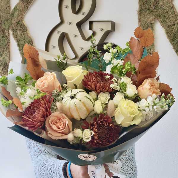 Handheld bouquet with roses, chrysanthemums, and a small pumpkin centerpiece