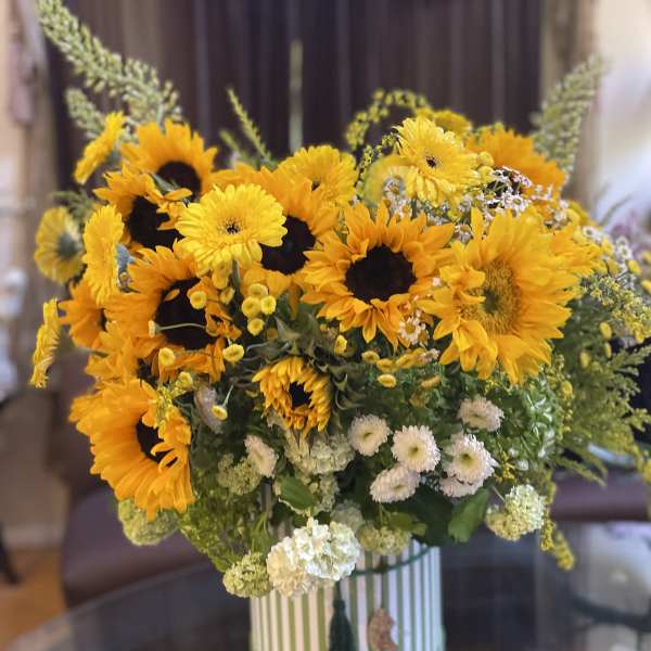 Sunflower bouquet in a striped round box with white accent flowers