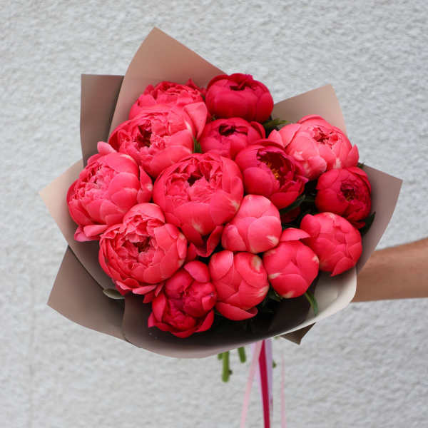 Bouquet of bright pink peonies wrapped in brown paper