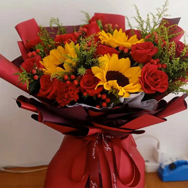 Bouquet of red roses and yellow sunflowers wrapped in red paper