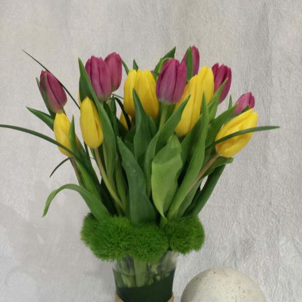 Bouquet of yellow and purple tulips in a glass vase