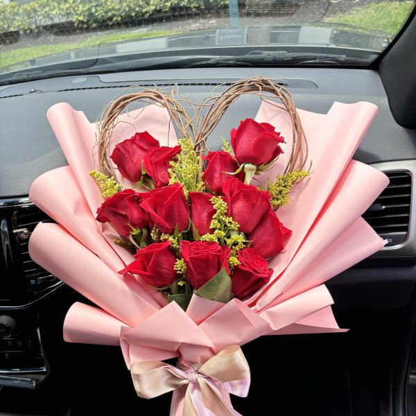 Bouquet of red roses wrapped in pink paper with a ribbon