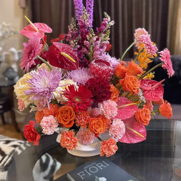 Bright mixed bouquet in a white vase with pink and orange blooms