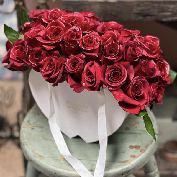Bouquet of red roses in a white hatbox with white ribbon