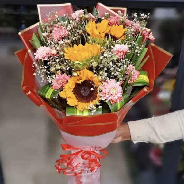 Bouquet of sunflowers and pink daisies wrapped in red paper