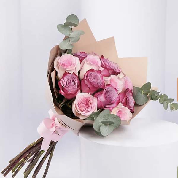 Pink rose bouquet wrapped in tan paper with eucalyptus accents