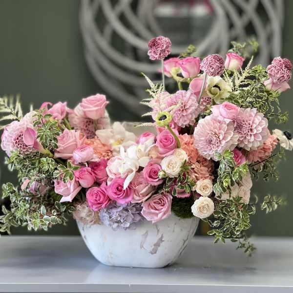 Pink floral arrangement in a white bowl vase