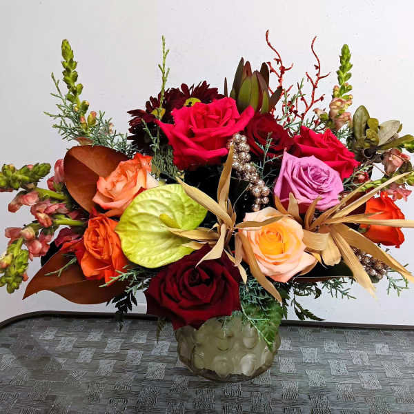 Mixed bouquet of roses and tropical accents in a glass vase