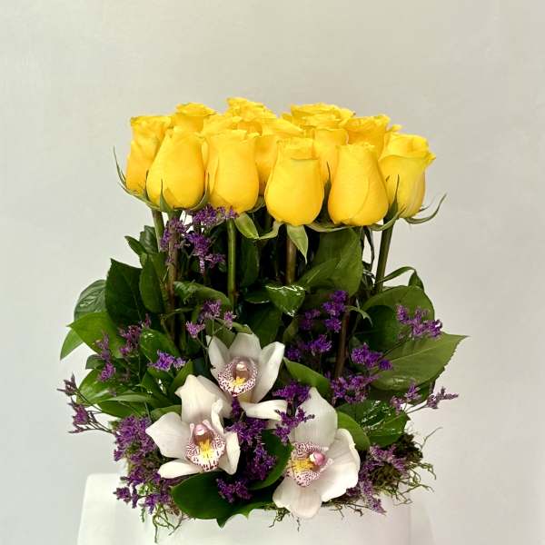 Yellow roses and white orchids arranged in a white vase
