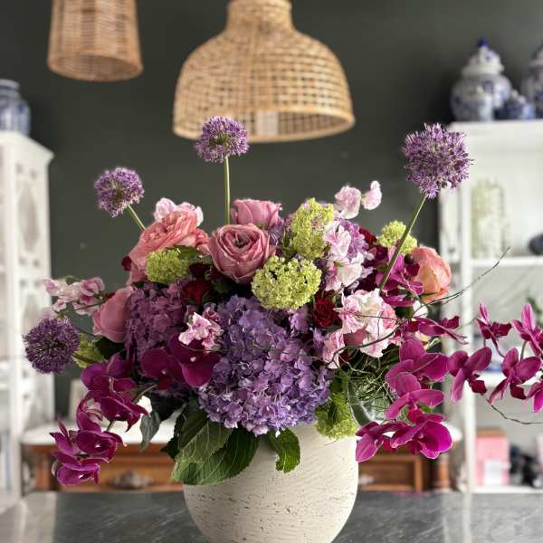 Pink and purple floral arrangement in a white vase