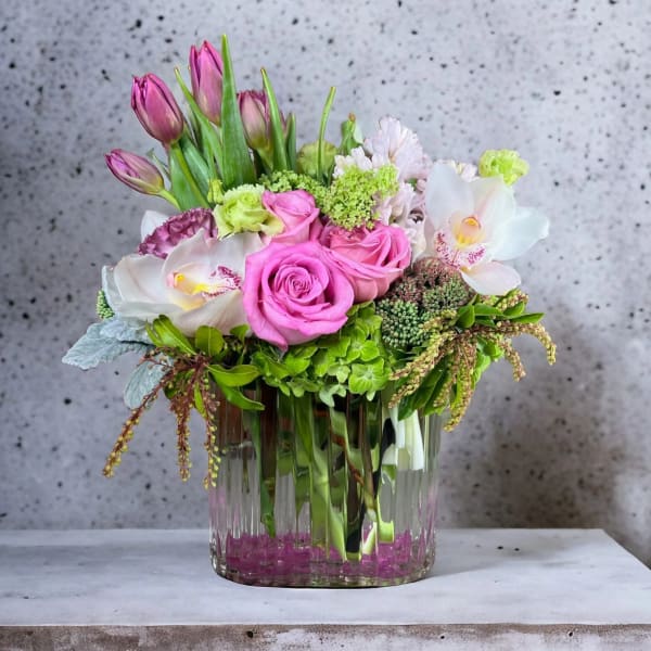 Pink roses and tulips arranged in a clear glass vase