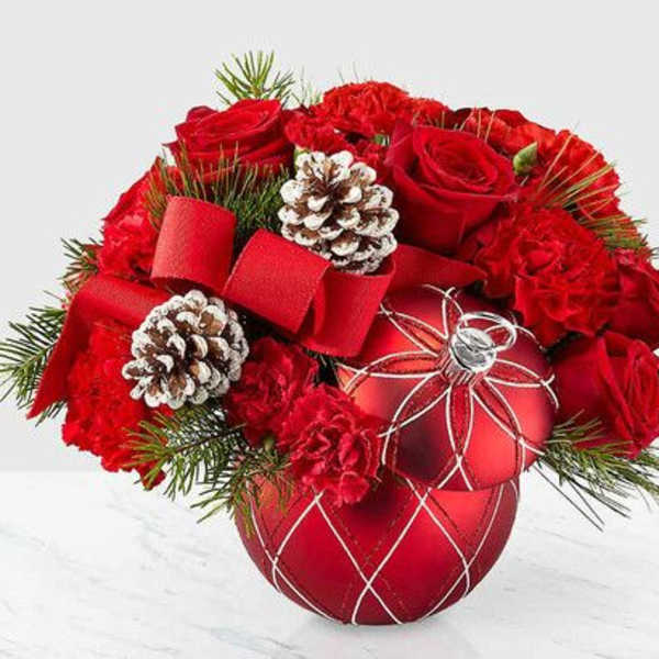 Red roses and carnations arranged with pinecones in a red ornament vase