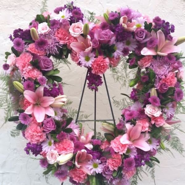 Heart-shaped floral wreath with pink and purple flowers on a stand