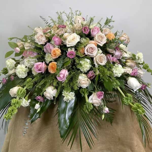 Large pastel bouquet of roses and carnations with trailing greenery