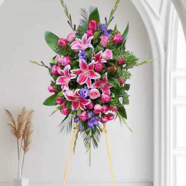 Standing floral spray with pink lilies and roses on a gold easel