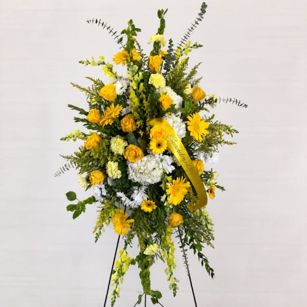 Tall yellow and white floral standing spray on an easel with a ribbon