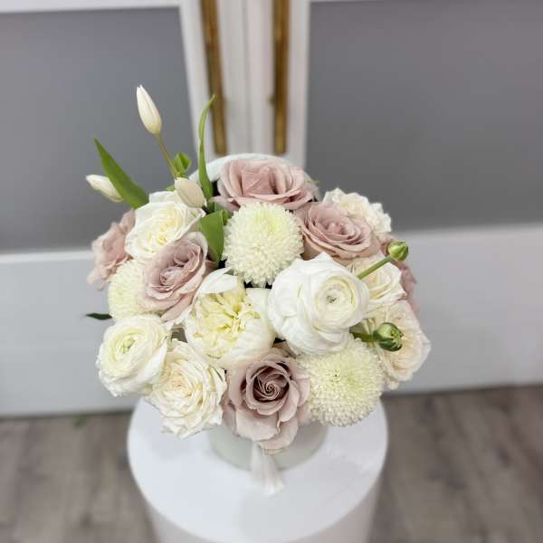 Bouquet of blush and white roses with round white blooms in a vase