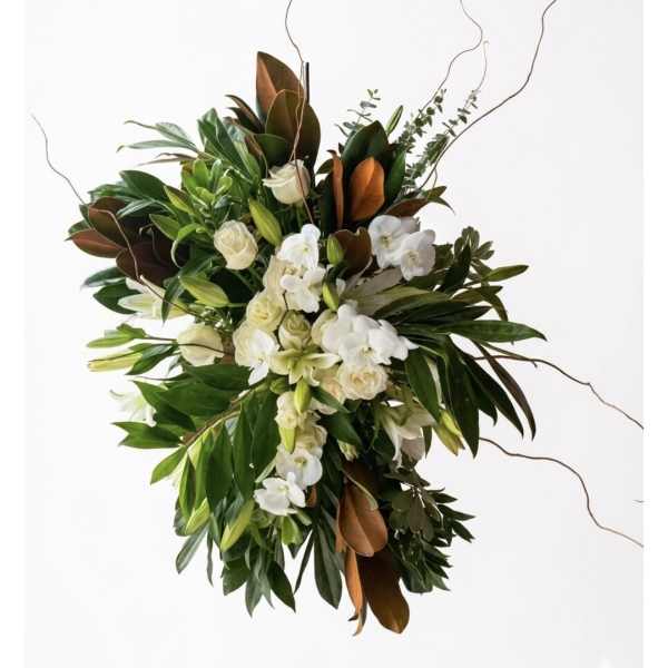 White orchids and cream roses in a lush green arrangement with curly branches