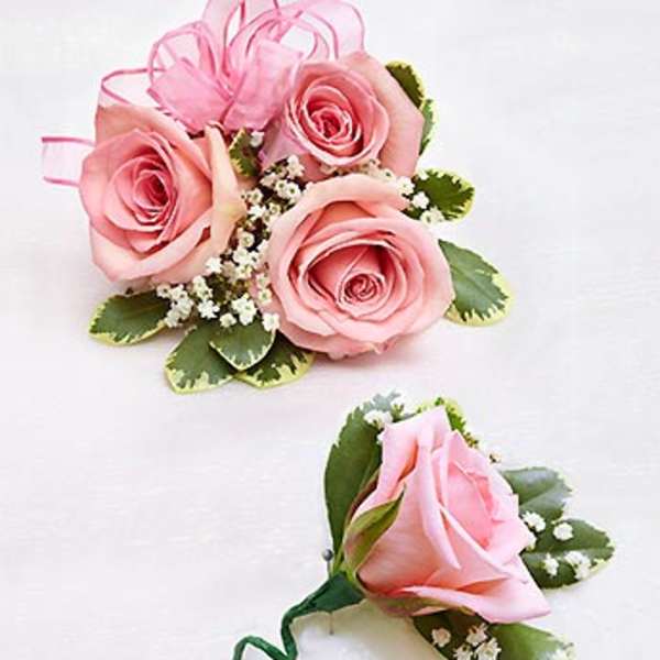 Pink rose corsage and boutonniere with ribbon and small white filler flowers