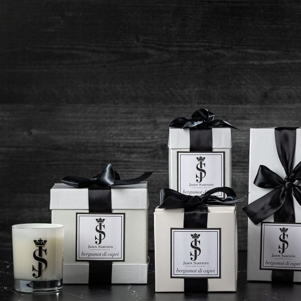 Gift boxes, a candle, and white flower stems in a glass vase