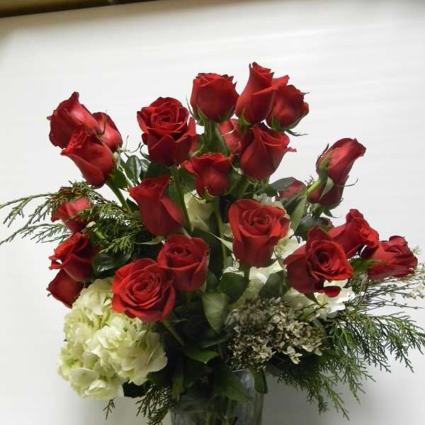 Red roses and white hydrangeas arranged in a clear glass vase