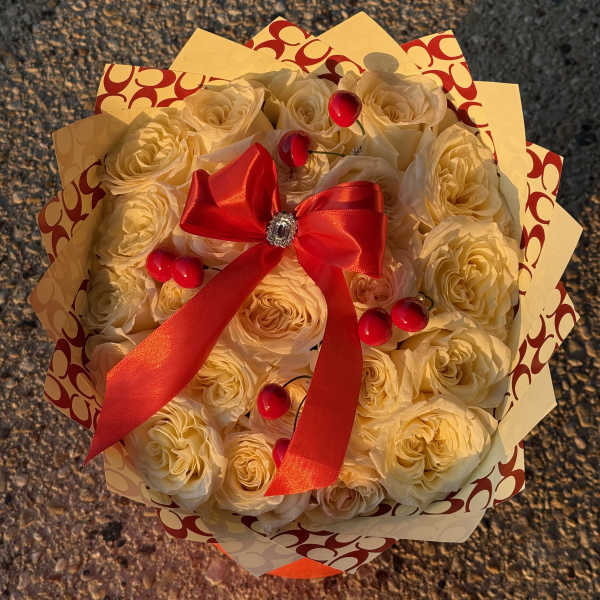 Bouquet of cream roses wrapped with patterned paper and a red ribbon
