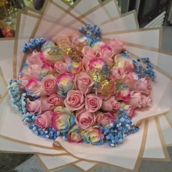 Bouquet of pink roses with blue filler flowers and pastel wrapping