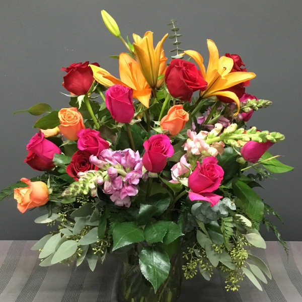 Mixed bouquet of roses, lilies, and snapdragons in a glass vase