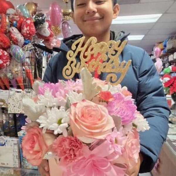 Pink and white flower arrangement with a gold "Happy Birthday" topper