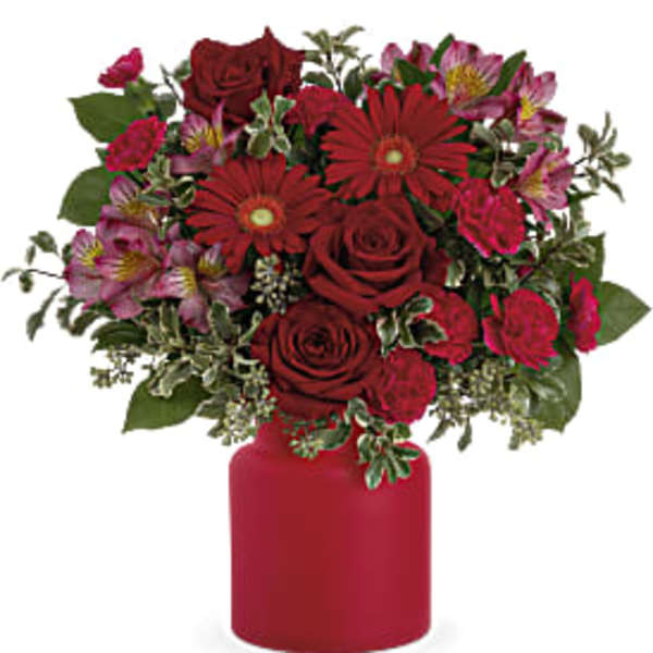 Red roses and pink flowers in a red vase