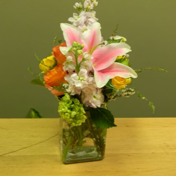 Pink lilies and mixed flowers in a clear glass vase