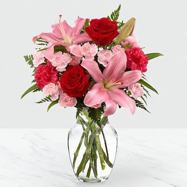 Pink lilies, red roses, and carnations in a clear glass vase