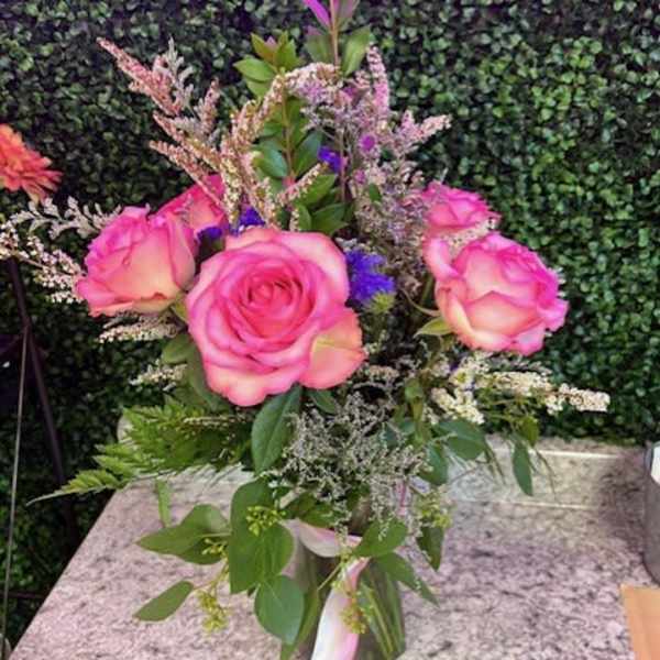 Pink roses arranged in a clear vase with mixed filler flowers