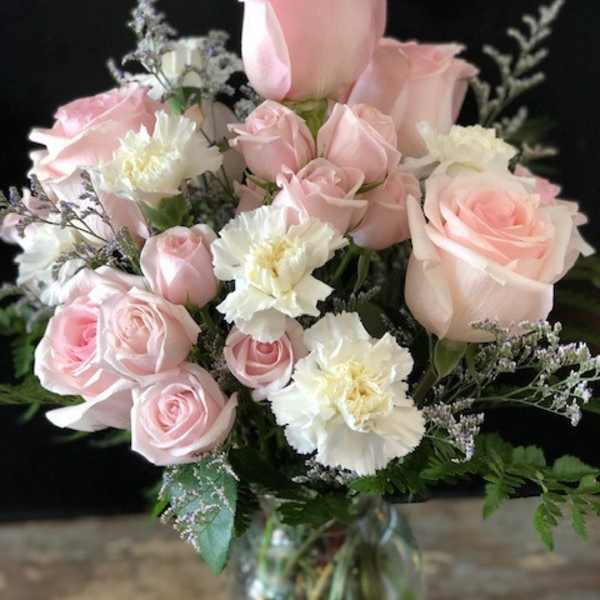Pink roses and white carnations arranged in a glass vase