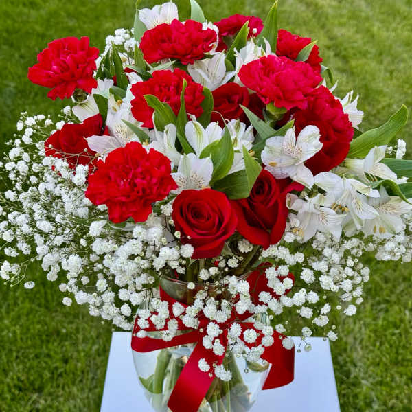 Red roses and carnations with white alstroemeria in a glass vase