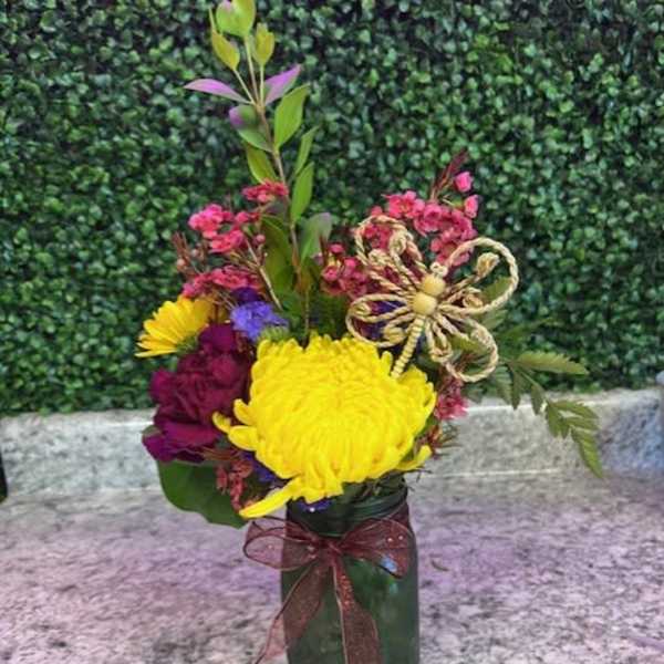Colorful bouquet in a green glass vase with a decorative bow