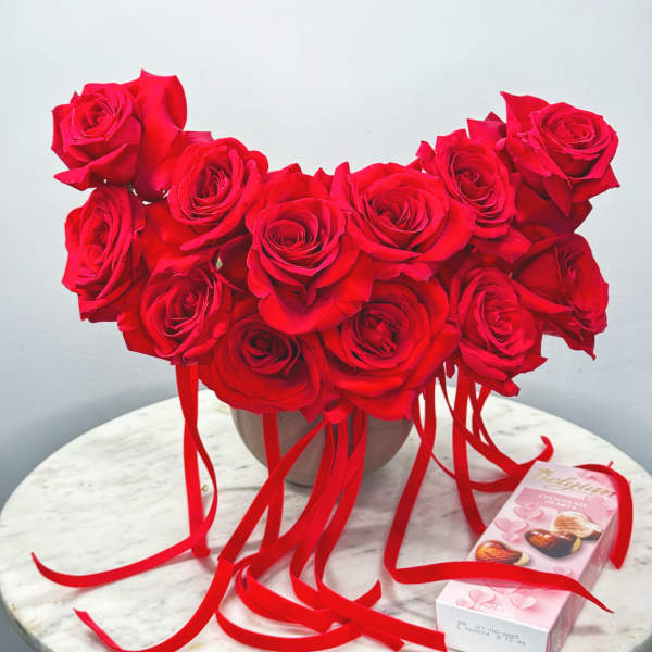 Heart-shaped bouquet of red roses with ribbon and a chocolate box