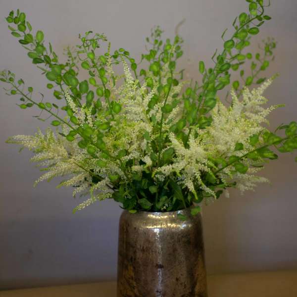 White filler flowers and green stems in a metallic vase