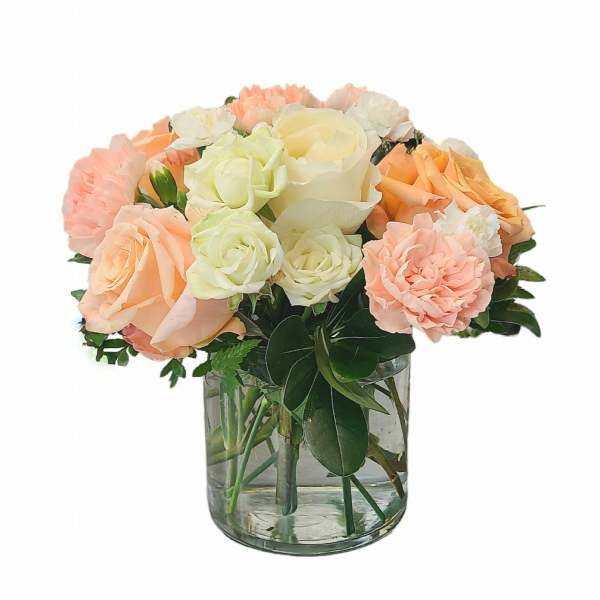 Peach and white roses with carnations in a clear glass vase