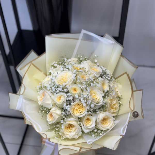 Bouquet of cream roses with baby's breath in pale wrapping
