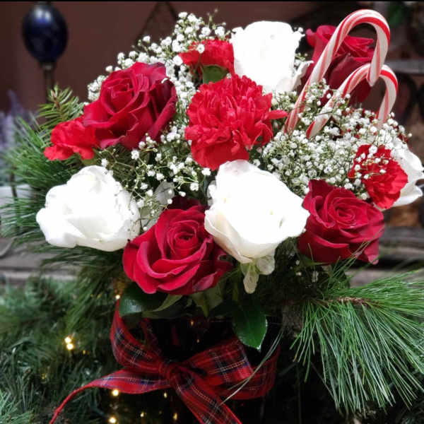 Red and white roses with carnations in a vase, accented by candy canes