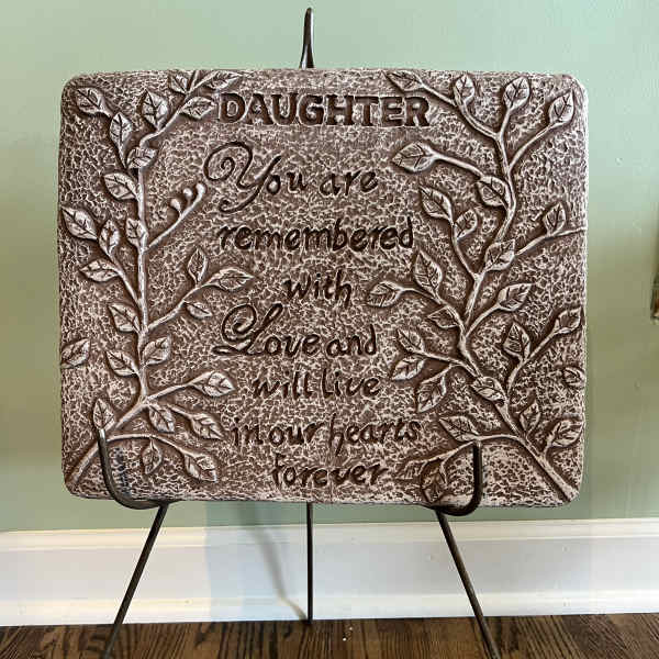 Decorative plaque on a metal stand with the words "Daughter, You are remembered with love and will live in our hearts forever"