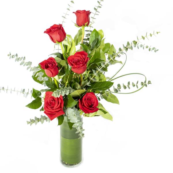 Red roses arranged in a tall glass vase with eucalyptus