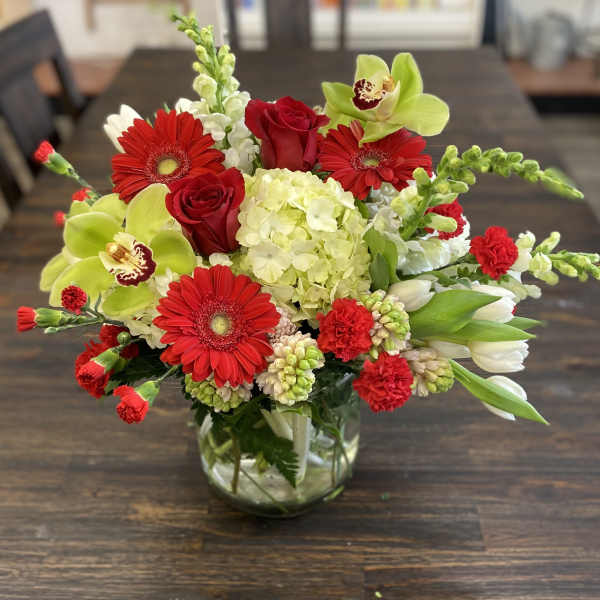 Red and green mixed flower arrangement in a glass vase